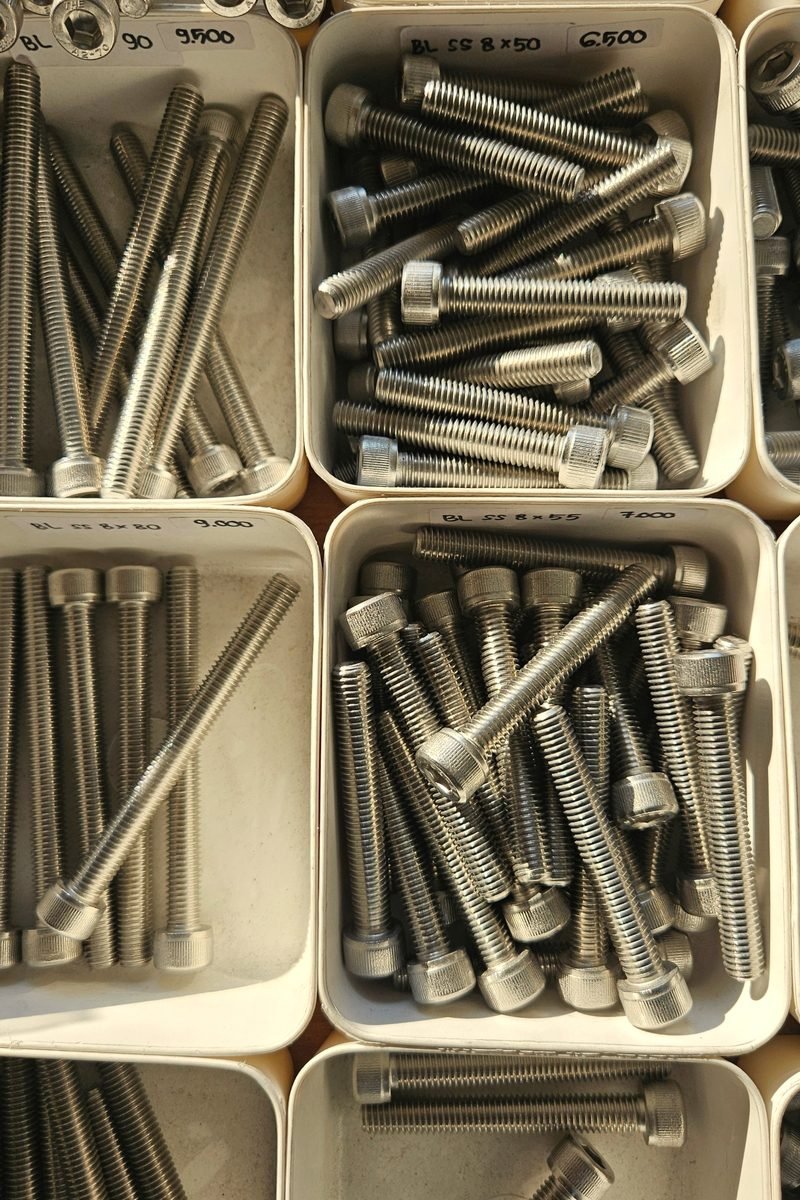 Hand-labelled bins of bolts and fasteners at a supply counter.